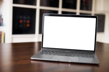 Sıradan bir dairede tahta bir masada boş beyaz masaüstü ekranı olan dizüstü bilgisayarın görüntüsü. Dizayn için boş ekranlı dizüstü bilgisayar.