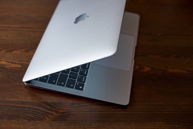 İngiltere, Newcastle on Tyne, 20 Temmuz 2022 - MacBook Air 2020-2022. Bir aralık MacBook Air ahşap bir masanın üzerinde duruyor. Kapaktaki Apple logosu ve parlayan klavyenin görüntüsü. Yan görünüm.