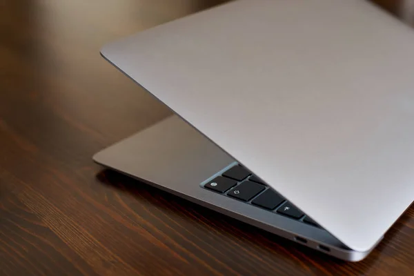Half Closed Laptop Aluminum Lid Stands Wooden Table Keyboard Visible — Φωτογραφία Αρχείου
