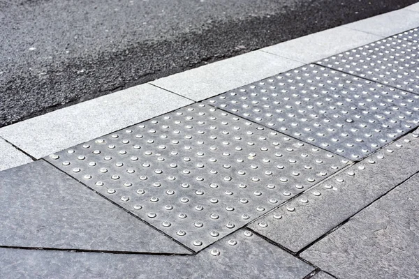 Tactile tiles for the blind. Panels for the blind laid on asphalt. Guide tape for the disabled. the inscription look right at the pedestrian crossing. Modern metal signs for the blind.