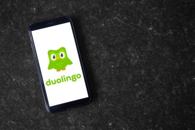 UK, Newcastle, August 21, 2022: The Duolingo logo on the screen of a modern smartphone, which lies on a surface of artificial stone
