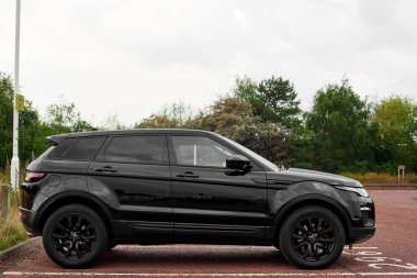 UK, Newcastle, 27 August 2022: Range Rover Evoque 2015 in black. Profile photo in the parking lot. Black wheels.