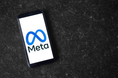 UK, Newcastle, August 21, 2022: The Meta logo on the screen of a modern smartphone, which lies on a surface of artificial stone