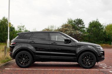 UK, Newcastle, 27 August 2022: Range Rover Evoque 2015 in black. Profile photo in the parking lot. Black wheels.