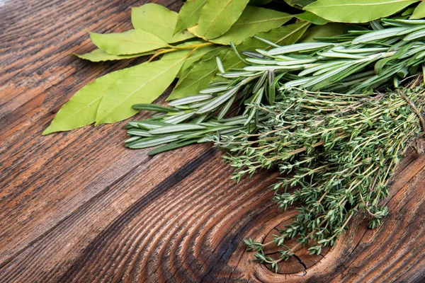 Fresh thyme, rosemary and laurel bay leaves bound on a wooden board — Stock Photo, Image