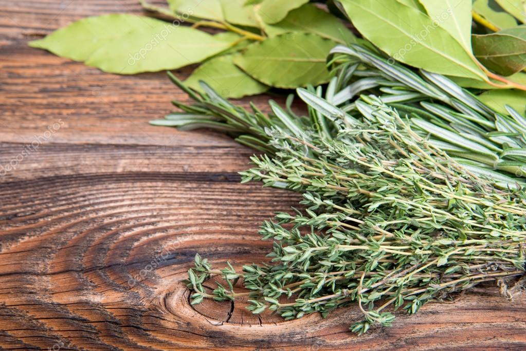 Fresh thyme, rosemary and laurel bay leaves bound on a wooden board — Stock Photo © moscowbear