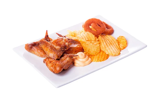 Жареные куриные крылышки с картошкой фри и луковыми кольцами — стоковое фото