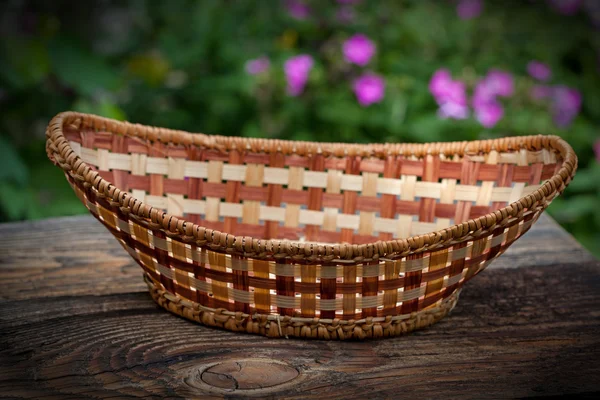 Cesta de vime vazia contra tábuas de madeira velhas no jardim — Fotografia de Stock