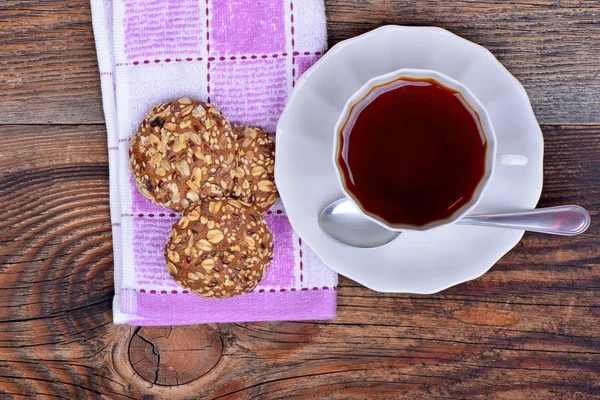 Organic cereal biscuits on a plate and tea on wooden background — Stock Photo, Image