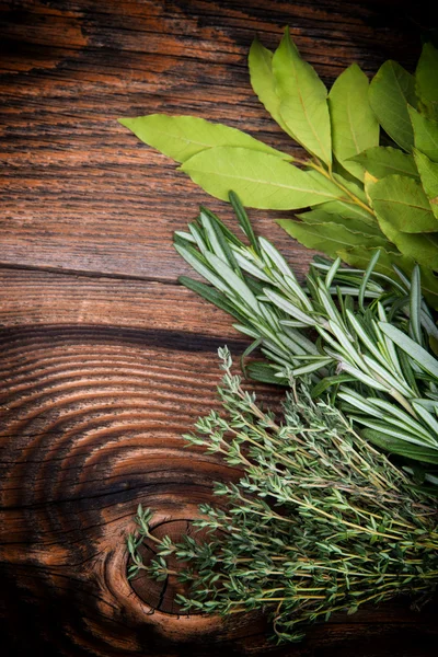 Fresh thyme, rosemary and laurel bay leaves bound on a wooden board — Stock Photo, Image