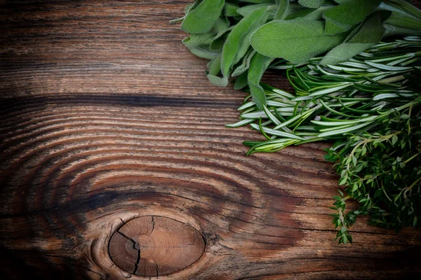 Fresh thyme, rosemary and sage leaves bound on a wooden board — Stock Photo, Image