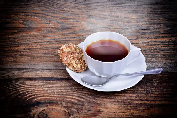 Biologische granen koekjes op een plaat en de thee op houten achtergrond — Stockfoto
