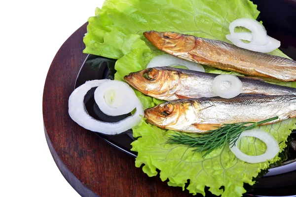 Копченая рыба, салат и лук на черной тарелке — стоковое фото
