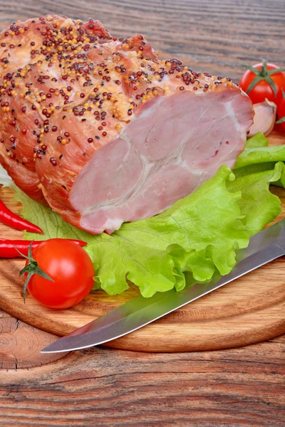 Baked pork neck, tomatoes, peppers, garlic and knife — Stock Photo, Image