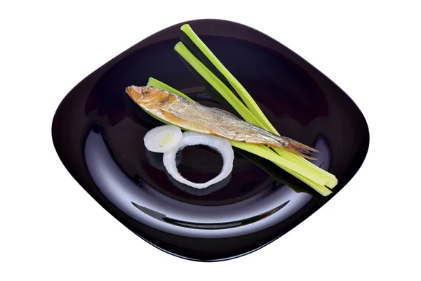 Smoked fish and onion on a black plate — Stock Photo, Image