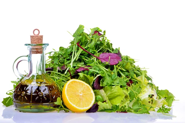 Mezcla de ensalada con botella de aceite de oliva y limón sobre fondo blanco —  Fotos de Stock