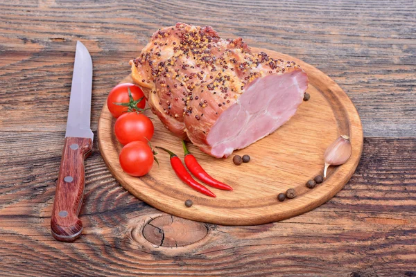 Baked pork neck, tomatoes, peppers, garlic and knife — Stock Photo, Image