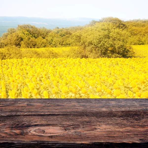 Field of sunflowers and empty old wooden deck table. Ready for product display montage — Stock Photo, Image