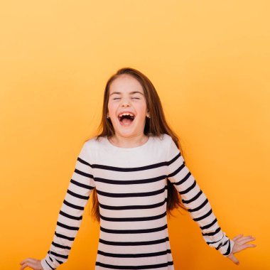 Sarı renkli arka planda parlak şık kıyafetler giyen sevimli küçük kız.