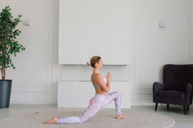 Sağlık konsepti. Genç ve güzel bir kadın modern bir odada yoga egzersizi yapıyor.