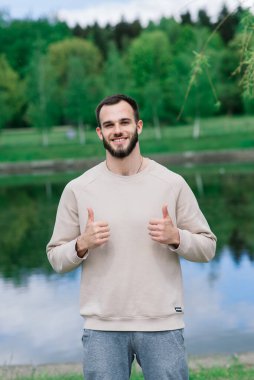 Beyaz tenli sporcu, sokak antrenmanı sırasında çapraz çubukta elini kaldırıyor..