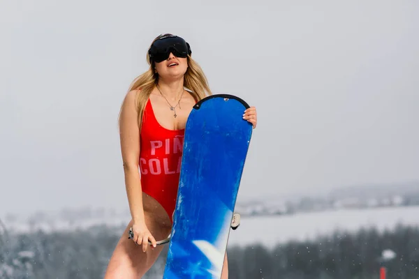 魅力的な女性は斜面にスノーボードと水着で身を包んだ — ストック写真