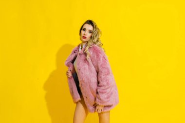 Lüks kürk manto ve vücut giysisiyle poz veren muhteşem genç bir kadın. Moda, güzellik. Stüdyo çekimi.