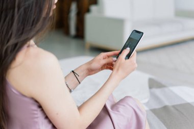 Akıllı telefon tutan kadın eli görüntüsü. Evde cep telefonu olan bir kadın. Seçici odak