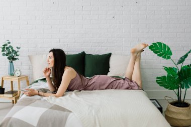 Masada oturan genç bir kız öğrenci, çalışırken akıllı telefon kullanıyor..