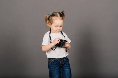 Kameralı çocuk. Stüdyo arka planında fotoğraf çeken küçük bir kız.