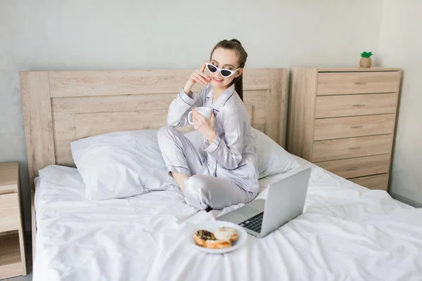 Foto Van Jonge Vrolijke Vrouw Pyjama Typen Laptop Glimlachen Terwijl — Stockfoto