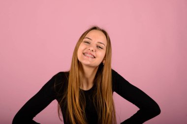 Mutluluk ve yüz ifadeleri kavramı. Gülümseyen kadın diş teli takıyor, pembe sırt.