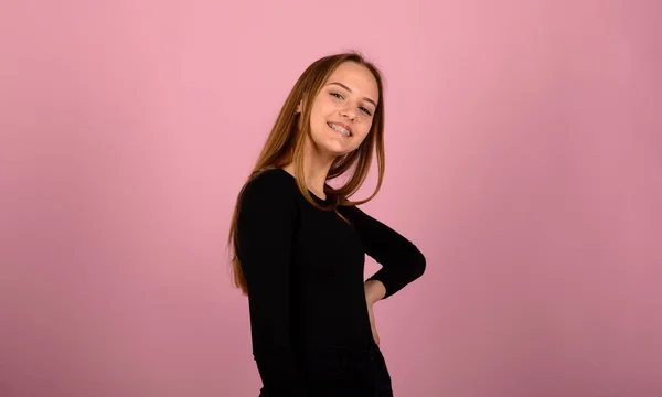 Mutluluk ve yüz ifadeleri kavramı. Gülümseyen kadın diş teli takıyor, pembe sırt.