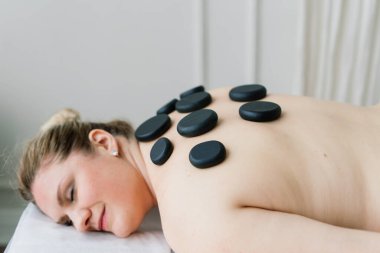 Şişman kadın kaplıca salonunda sıcak taş kol masajı yaptırıyor. Terapi, sağlık ve rahatlama konsepti.