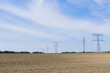 Gökyüzü arka planında elektrik iletim hatları, bir sonbahar alanı