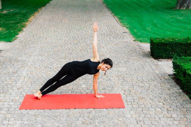 Olgun Asyalı kadın parkta yoga yapıyor. Yaşam tarzı uygunluğu ve sağlıklı olma kavramı.