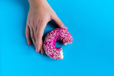 Yarı yenmiş pembe donutla el ele tutuşmak. Yarısı yenmiş çörek..