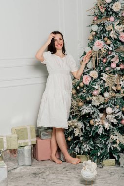 Kadın Noel ağacını süslüyor, gülümsüyor, yeni yıl arifesinde oturuyor.