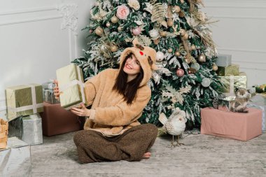 Kadın Noel ağacını süslüyor, gülümsüyor, yeni yıl arifesinde oturuyor.