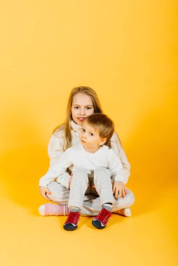Happy brother and sister studio portrait on a yellow background