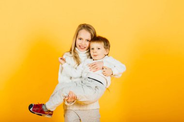 Happy brother and sister studio portrait on a yellow background