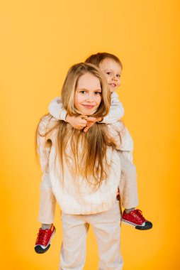 Happy brother and sister studio portrait on a yellow background