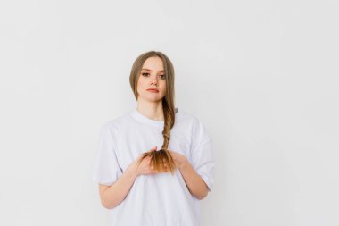 Güzel bayan makyaj yapıyor ve yatak odasında saç yapıyor. Oldukça uzun saçlı çekici bir genç bayan.