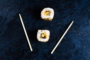 Ahşap çubuklarla siyah masada suşi. Restoranda Japon yemeği yemek..