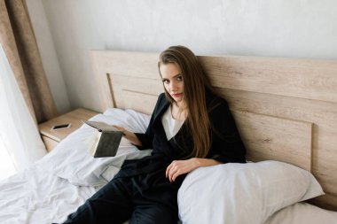 Kanepede uzanan ve evde kitap okuyan bir kadın.