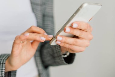 Masada oturan genç bir kız öğrenci, çalışırken akıllı telefon kullanıyor..