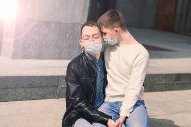 Tıbbi maske takan genç eşcinsel çift şehirde sarılıyor..