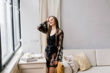 Uzun bacaklı ve uzun saçlı genç bir kadın. Sabahları rahat bir dairede kanepede poz veriyor.