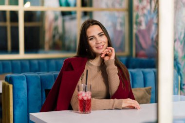Happy woman at an outdoors cafe drinking and smiling