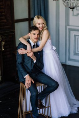 Klasik bir stüdyonun içinde şirin bir düğün çifti. Öpüşüyorlar ve sarılıyorlar..